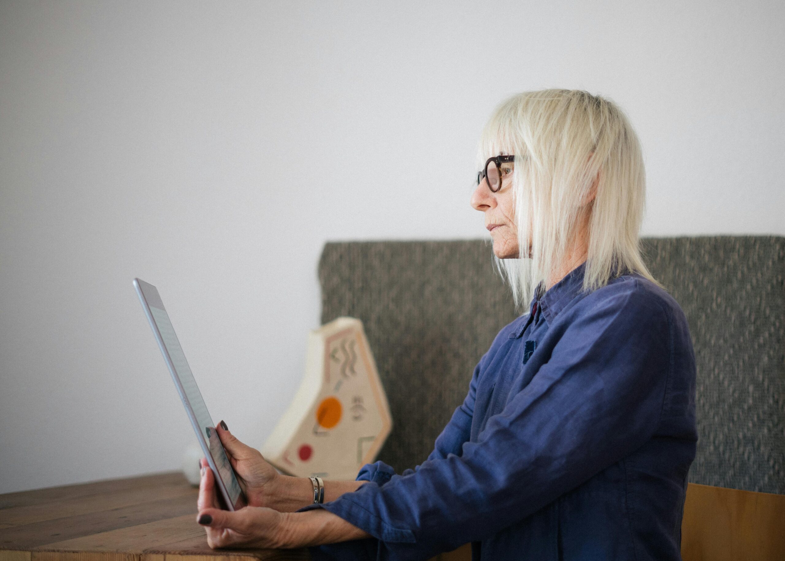 elderly woman accessing online therapy via tablet at home.